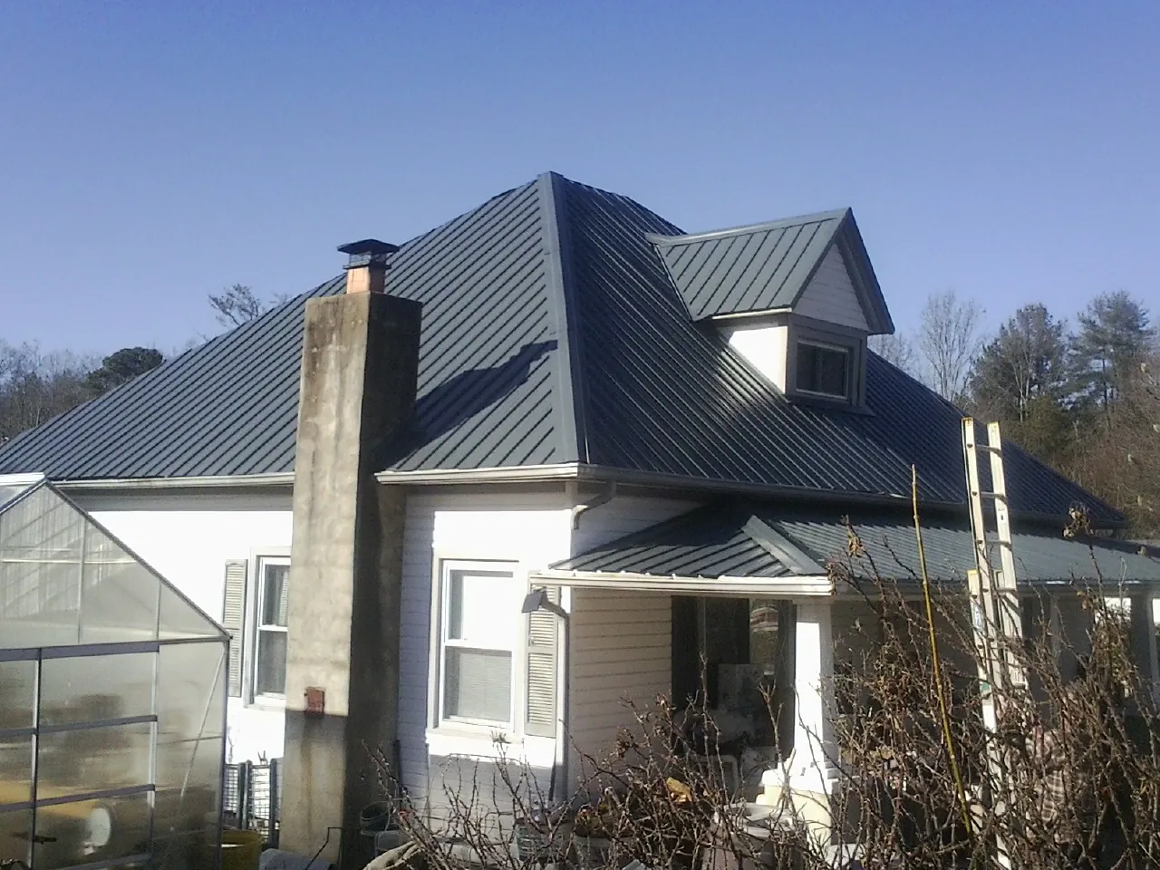 Dark blue standing seam metal roof on a white farmhouse with dormer — Slate & Tile Roof Repair by Roofing Brothers in Fort Valley