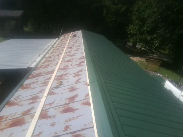 Old rusted panels beside newly installed green metal roofing — Wind Damage Roof Repair by Roofing Brothers in Fort Valley