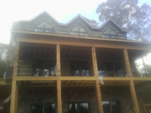 Dormers and porch framing on a large log home under construction — Roof Coating work by our crew in Fort Valley