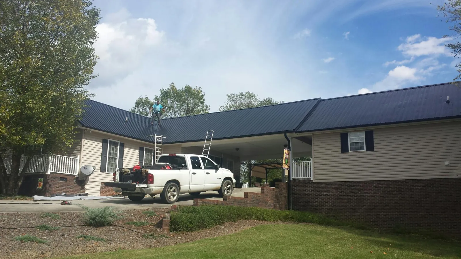 Black metal roof over a home and attached breezeway with ladders set in Fort Valley