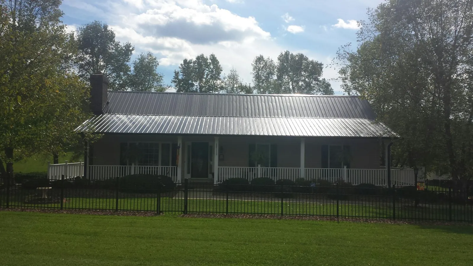Gray metal roof on a brick ranch with a full width front porch — Gutter Guard Installation work by our crew in Fort Valley
