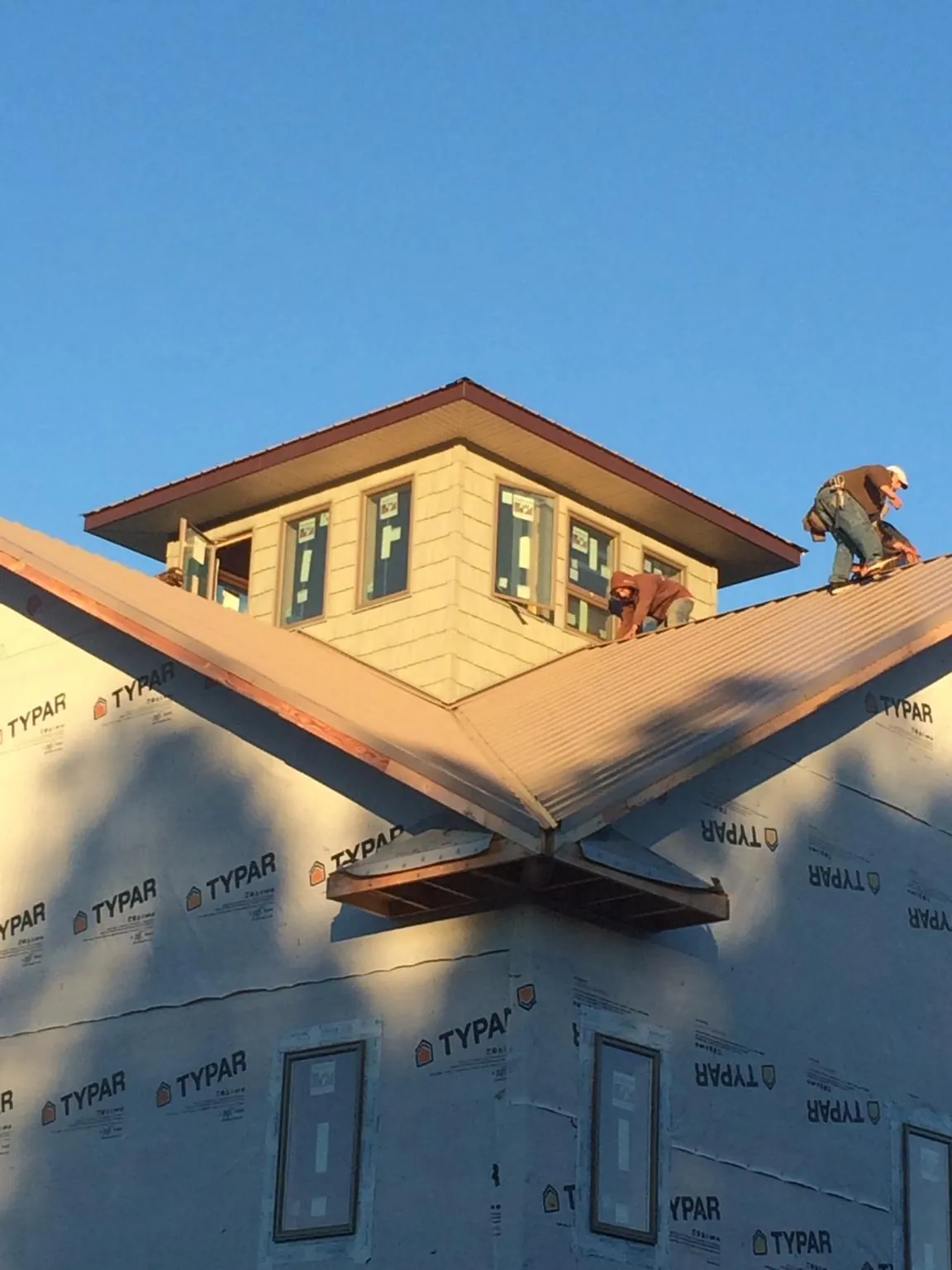 Roofers working around a rooftop cupola on a new metal roof at sunset — Roof Waterproofing in Fort Valley by Roofing Brothers